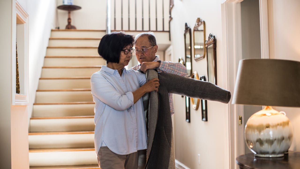 Senior man helping wife with coat