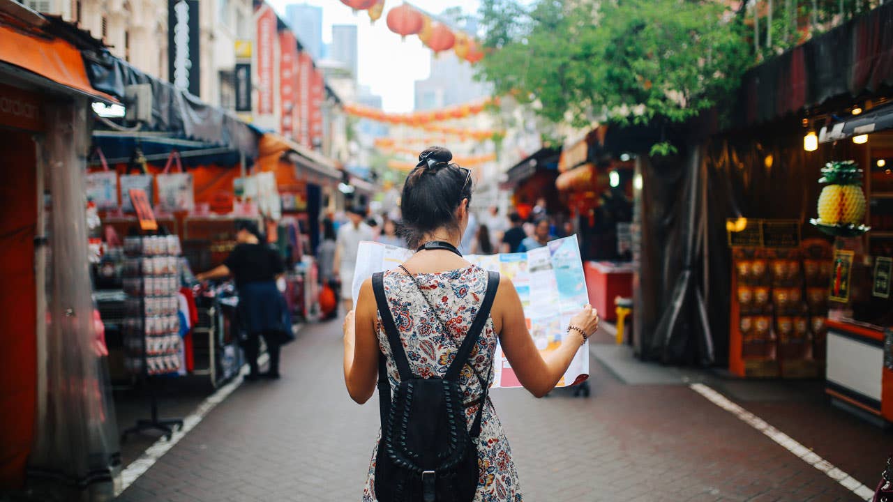 woman walking on city street and looking at map