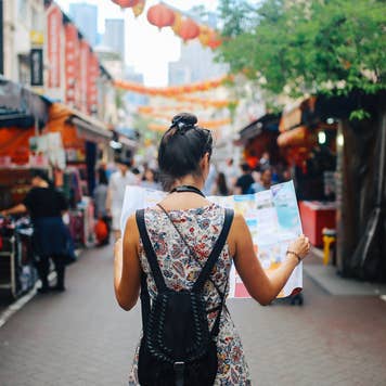 woman walking on city street and looking at map