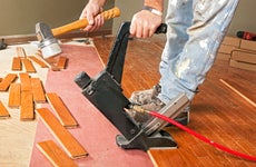 A carpenter lays hardwood flooring