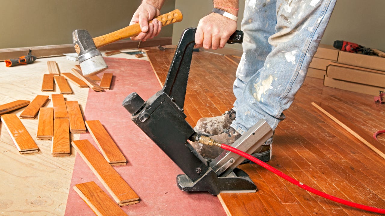 A carpenter lays hardwood flooring
