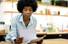 Black woman at home reading a letter in the mail