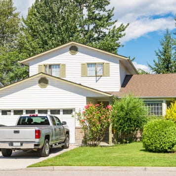 A single-family home with attached garage and two cars in the driveway