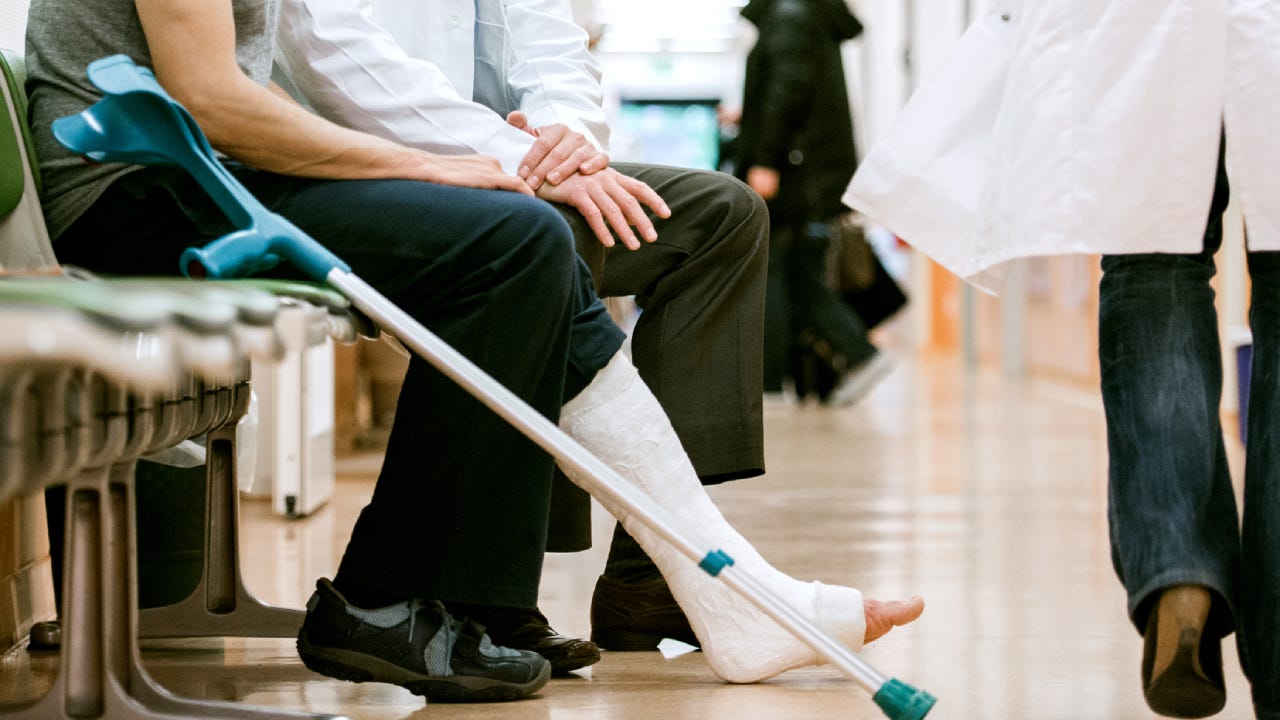 Man With Cruches And Cast On Broken Leg Consulting Doctor