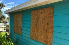 Outside of a home with the windows boarded up.