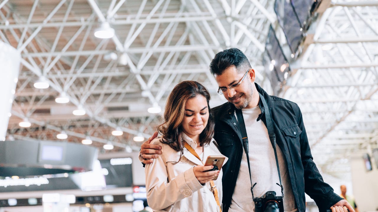 Couple at airport looking at smartphone