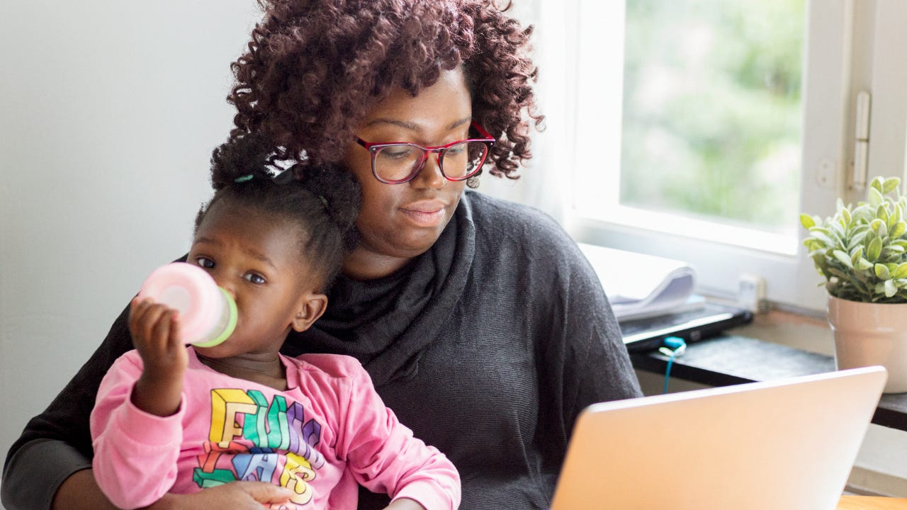 Mother working on laptop with toddler