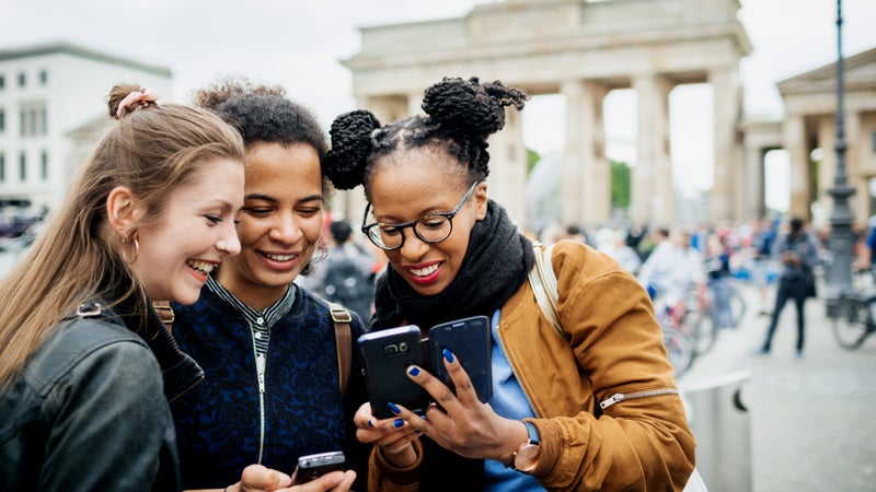 3 Young women looking at smartphone in Europe