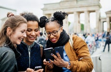 3 Young women looking at smartphone in Europe