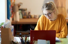 A young woman at home with her laptop making notes