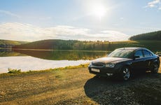 Car parked by lake on rolling landscape