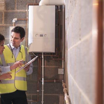 Energy advisor discussing usage of energy efficient boiler with woman in home