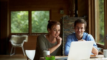 A young couple look at their laptop computer in a cottage