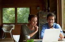 A young couple look at their laptop computer in a cottage