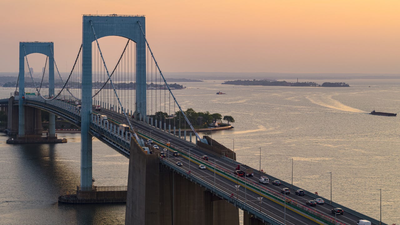 Moderate traffic on Throgs Neck Bridge over East River connecting Queens and Bronx Boroughs, New York, at sunrise.