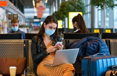 Woman in mask on a smartphone in airport