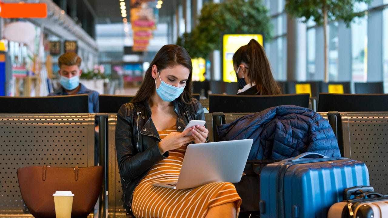 Woman in mask on a smartphone in airport