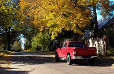 Red pickup truck parked on leafy neighborhood street in Autumn