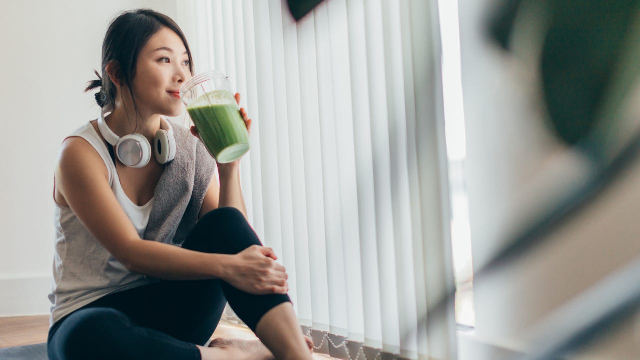 Young Asian Woman Drinking Green Smoothie After Yoga