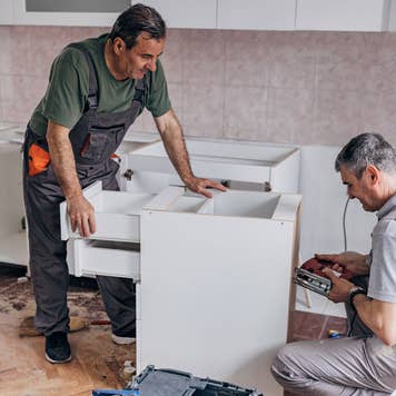two men working on a cabinet during kitchen renovation