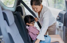 Senior asian woman buckle up her granddaughter in car