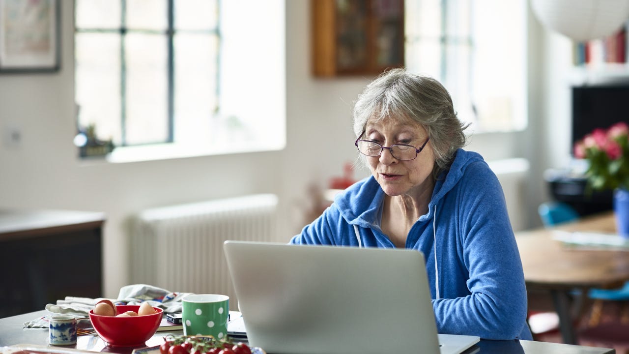 Senior woman wearing glasses using laptop at home