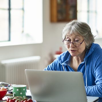 Senior woman wearing glasses using laptop at home