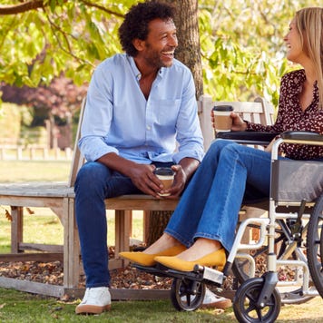 Woman in wheelchair talks with man sitting on a bench