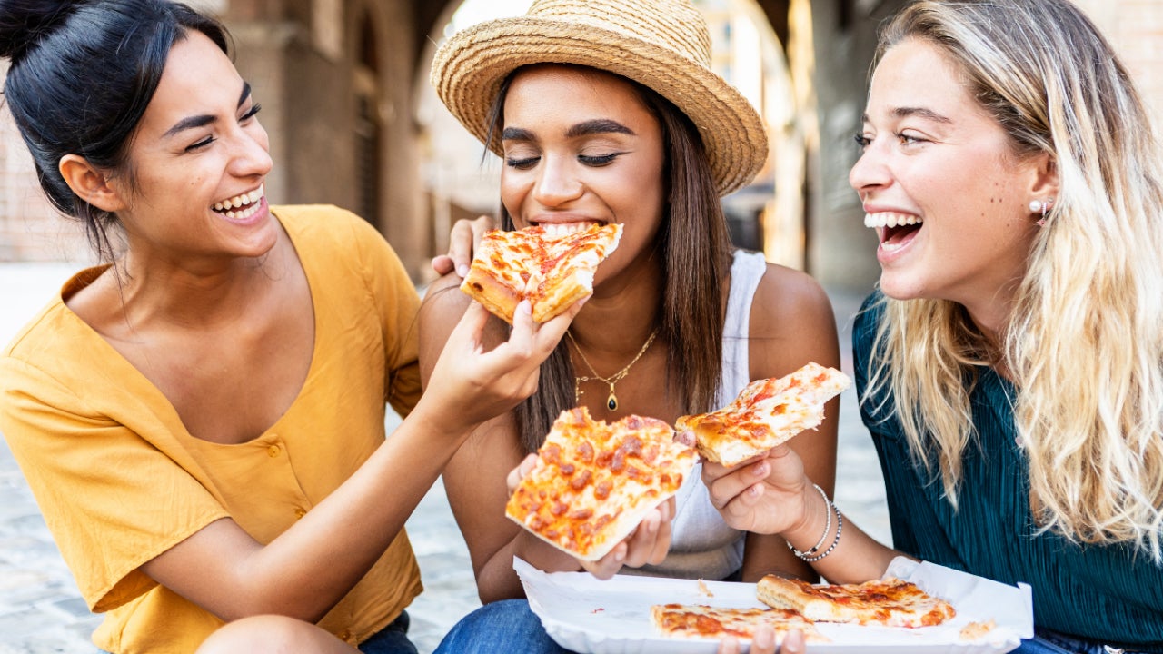 Millennial women eating pizza