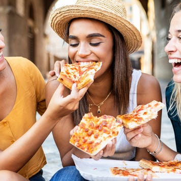 Millennial women eating pizza