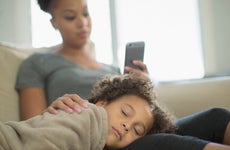 A mother and daughter at home, mother looking at phone, daughter sleeping