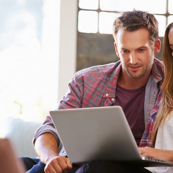 A couple looks at a laptop at home on their couch