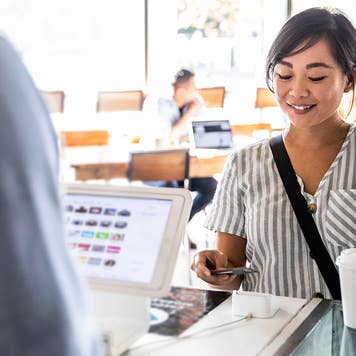Young woman using credit card reader at coffee shop