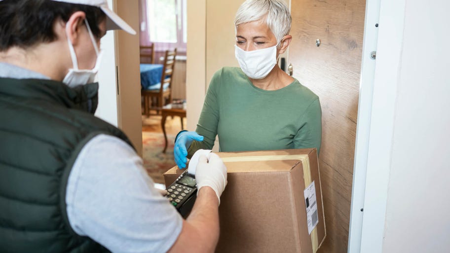 Senior woman accepts package from delivery man at her doorstep