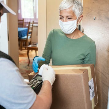 Senior woman accepts package from delivery man at her doorstep