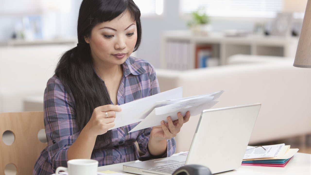 Serious Asian woman looking at mail in home office