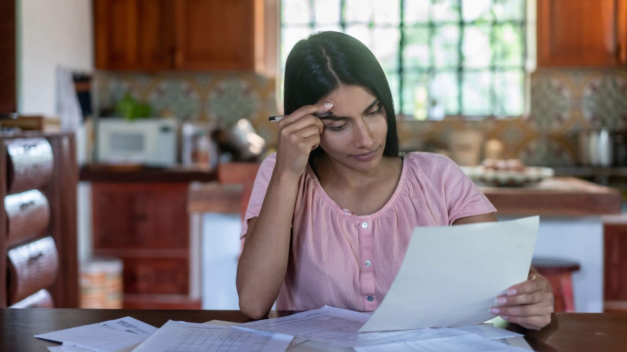 Young concerned woman looks at her bills at the kitchen table