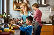 Same sex couple cooking with son in kitchen