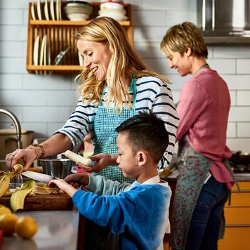 Same sex couple cooking with son in kitchen