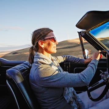 woman driving convertible at sunset