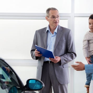 African American father and son discussing with a car salesperson.