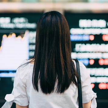 Rear view of businesswoman looking at stock exchange market display screen board in downtown financial district