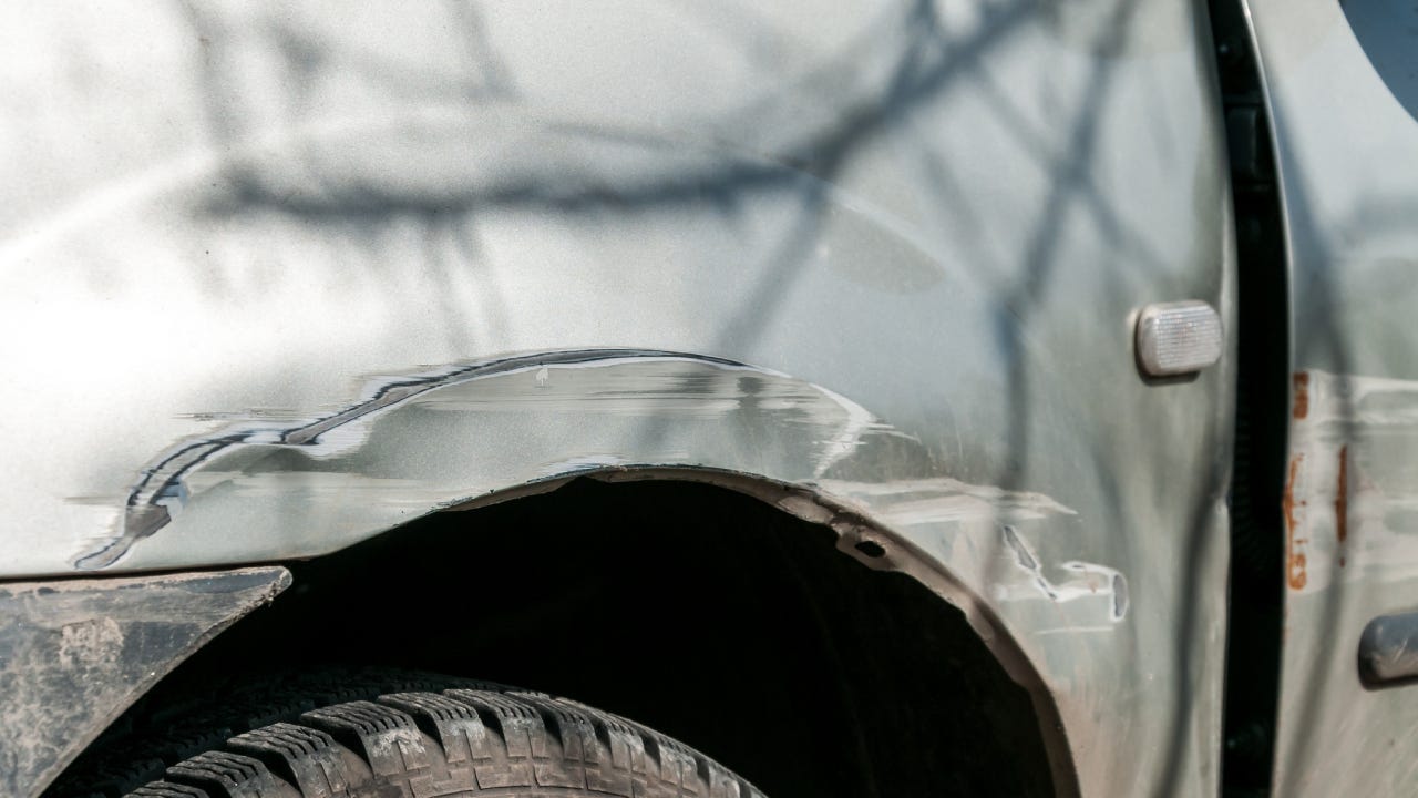 Silver damaged car with dented aluminum metal body scratched and peeling paint