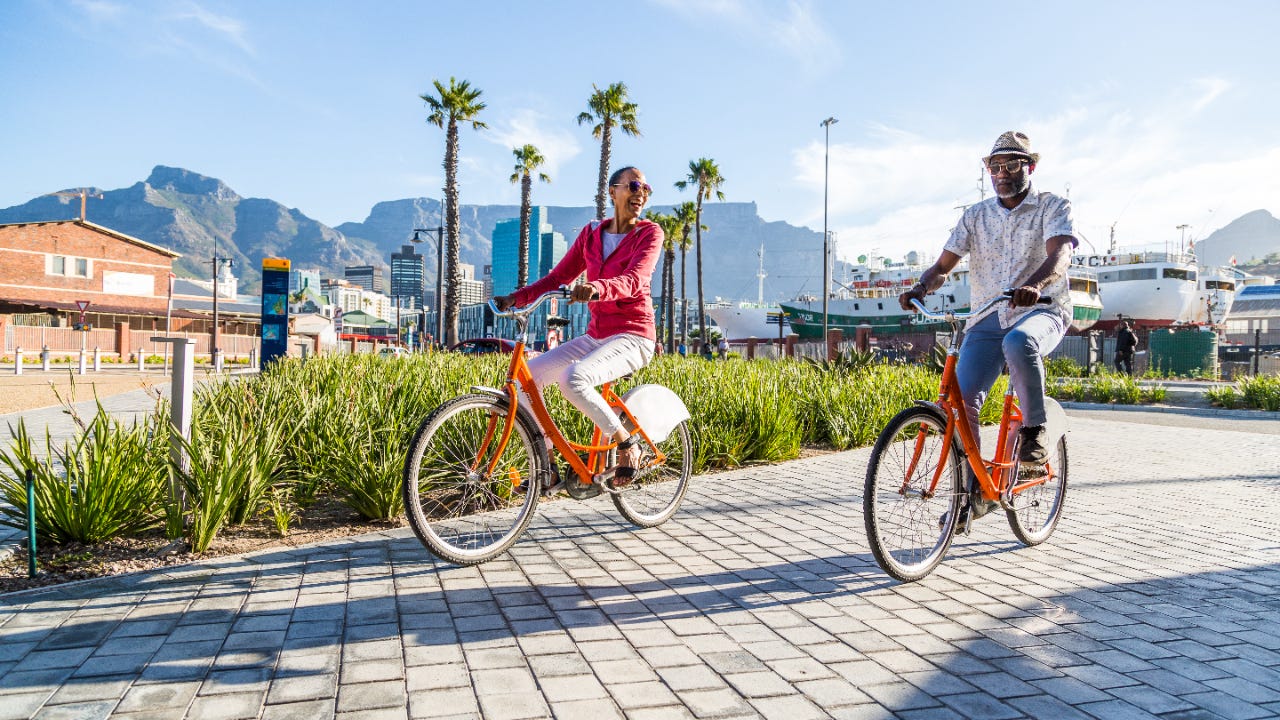 An older couple bikes through a public plaza