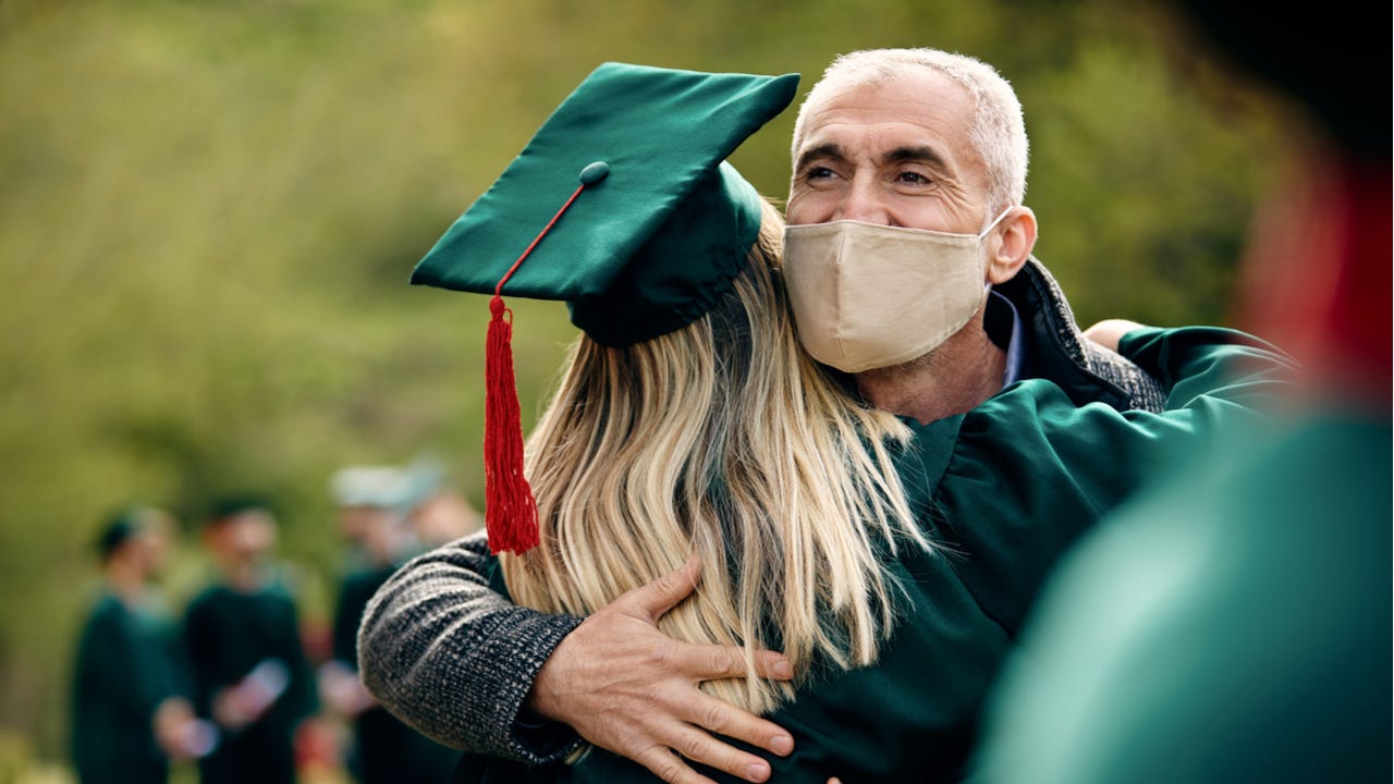 Father with mask hugs daughter at graduation