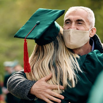 Father with mask hugs daughter at graduation