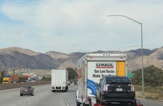 A U-Haul truck towing a car on a California highway