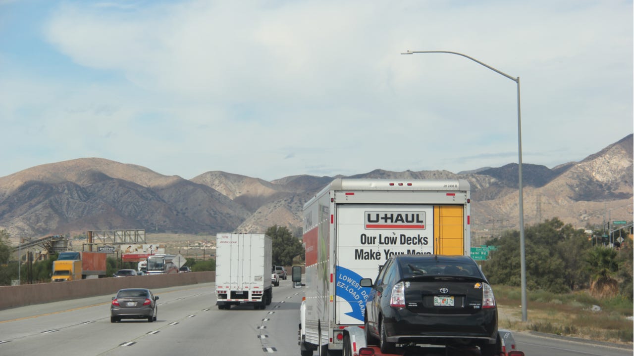 A U-Haul truck towing a car on a California highway