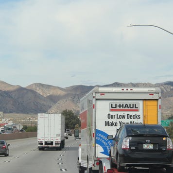 A U-Haul truck towing a car on a California highway
