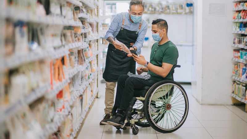 Man in wheelchair shopping in pharmacy or grocery store